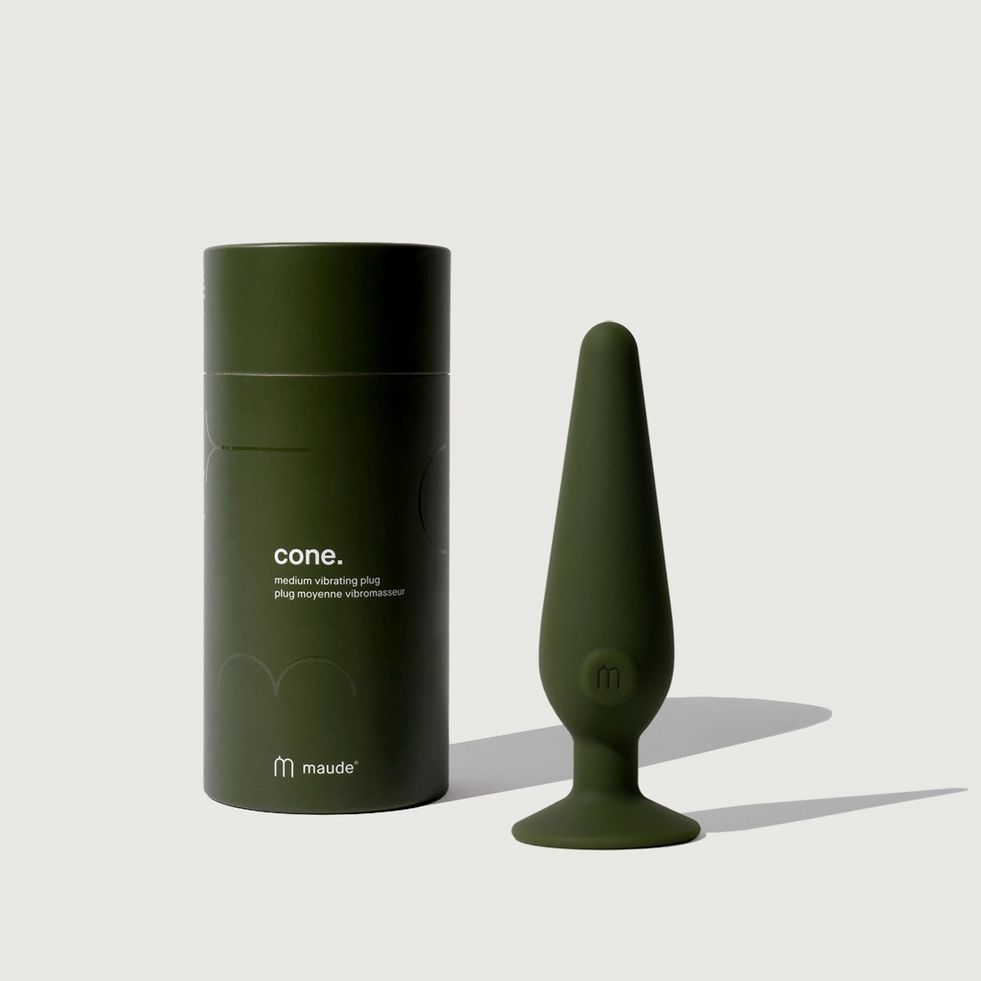 Product shot of the Maude Code medium vibrating plug in green, displayed alongside its packaging.